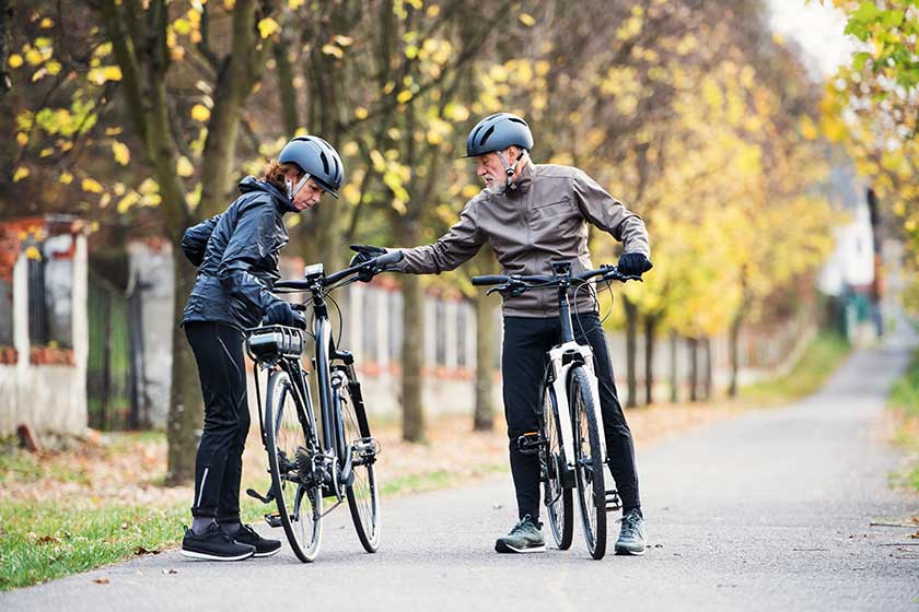 Active senior couple with electrobikes standing outdoor