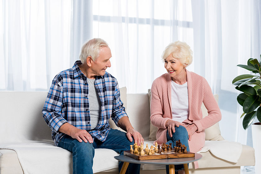 concentrated senior couple playing chess at home on couch concentrated senior couple playing chess at home on couch