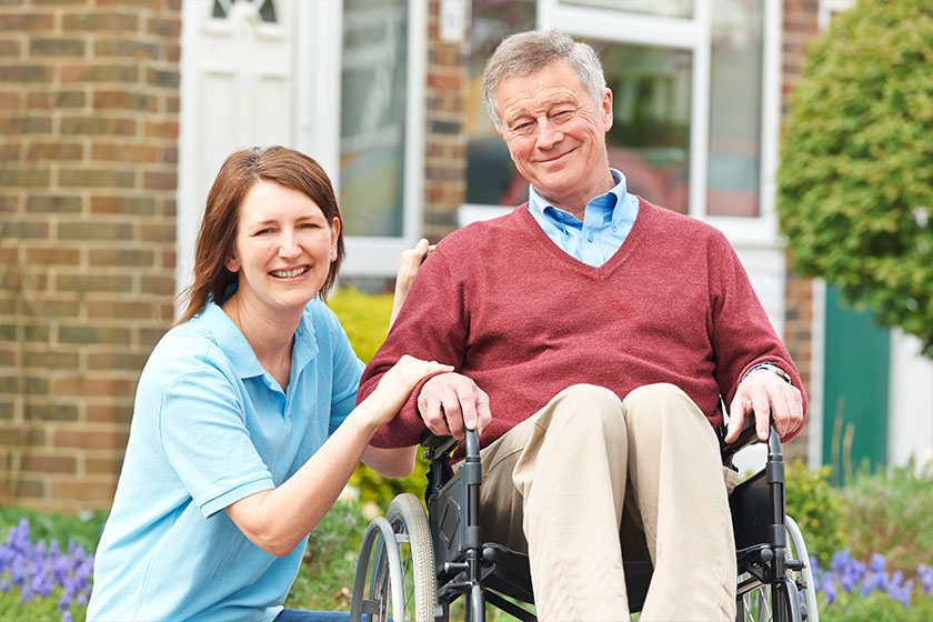 enior man in wheelchair posing with young female caregiver