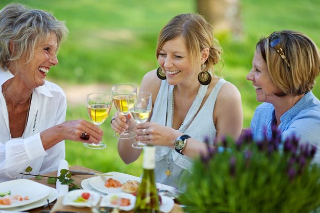 Family Toasting White Wine At Dining Table