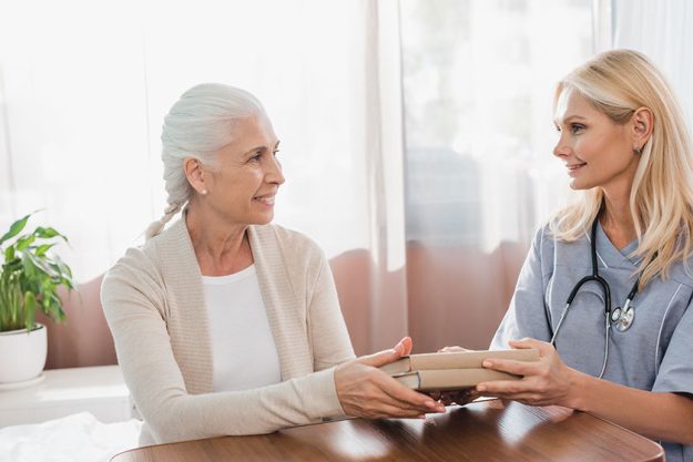 Nurse and senior patient with books