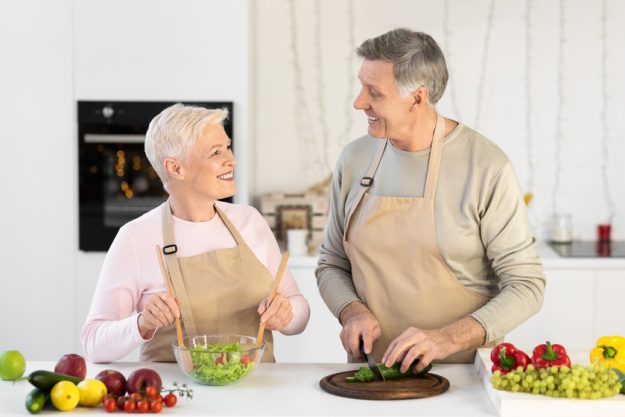 Cheerful Aged Couple Cooking Salad Preparing Dinner In Modern Kitchen couple-talking