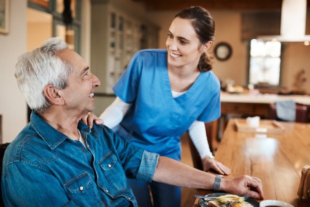 Breakfast and a smile, great start to the morning. a young nurse checking up on a senior man during breakfast at a nursing home. a senior man during breakfast at a nursing home