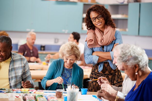Group Of Retired Seniors Attending Art Class In Community Centre With Teacher Group Of Retired Seniors Attending Art Class In Community Centre With Teacher
