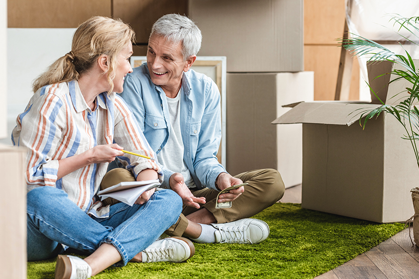 Happy senior couple sitting on carpet and counting money during relocation Happy senior couple sitting on carpet and counting money during relocation