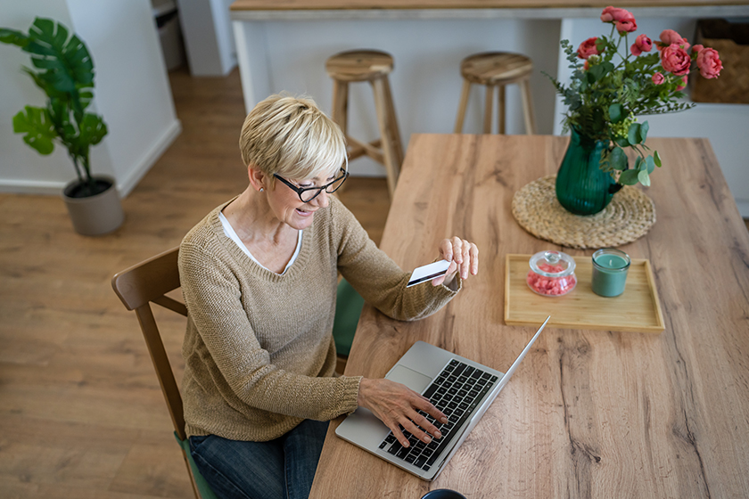 One mature senior woman grandmother sit at home use credit or debit card for online shopping browse internet stores use laptop computer buying stuff real people copy space One mature senior woman grandmother sit at home use credit or debit card for online shopping browse internet stores use laptop computer buying stuff real people copy space