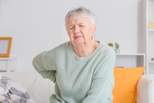 Senior woman suffering from back pain at home
