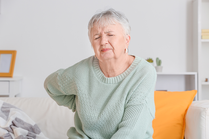 Senior woman suffering from back pain at home