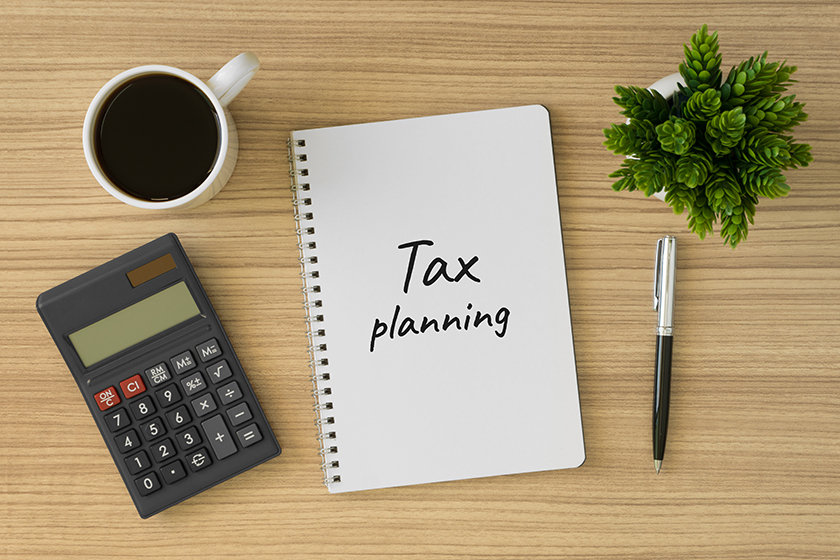 Tax planning written on notebook. Top view of wood desk with office supply