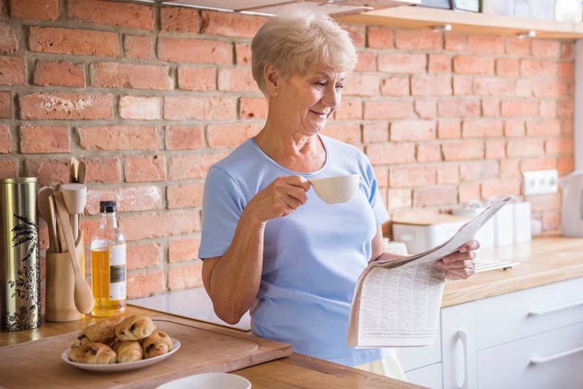 Woman drinking tea and reading paper