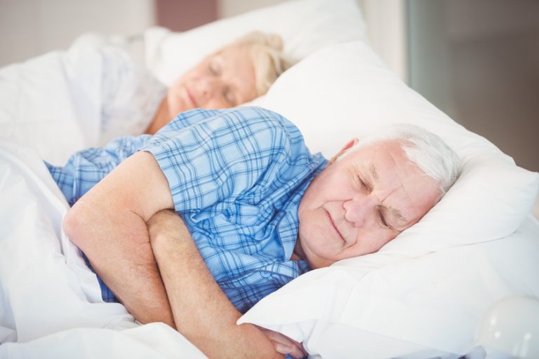 Senior couple sleeping on bed at home