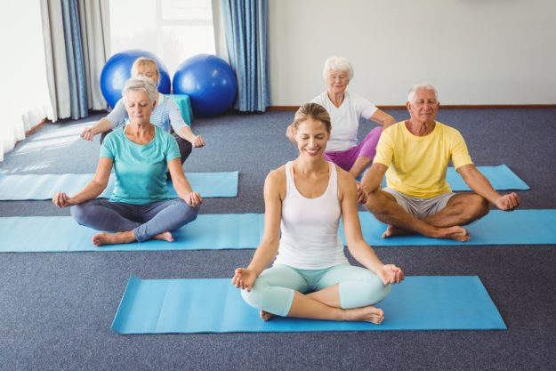 Seniors relaxing in lotus position during fitness class How Spiritual Activities Help Those Living With Dementia