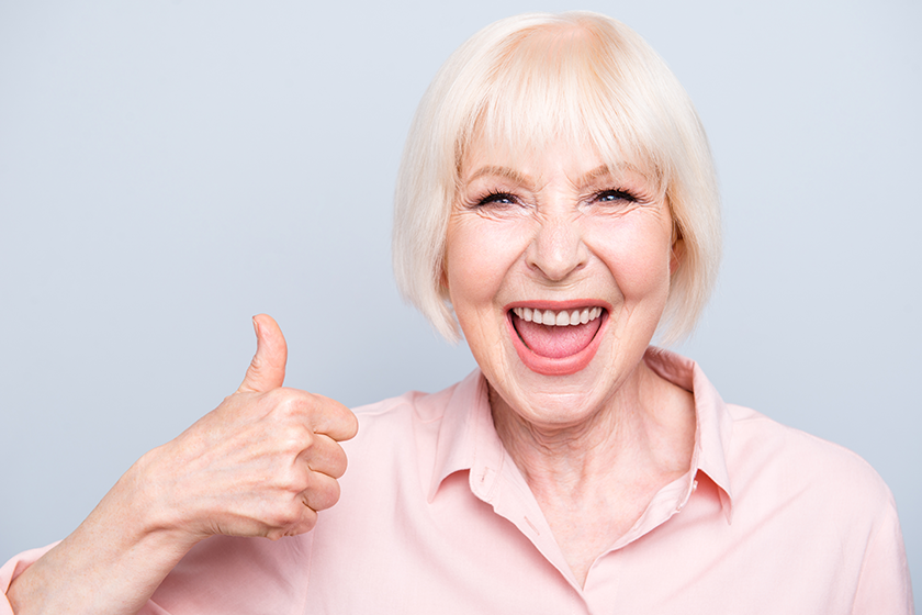 Old excited lady showing thumbs up gesture