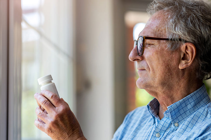Senior man taking prescription medicine at home