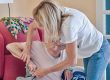 An 83-year-old senior in her wing chair and the geriatric nurse helps her