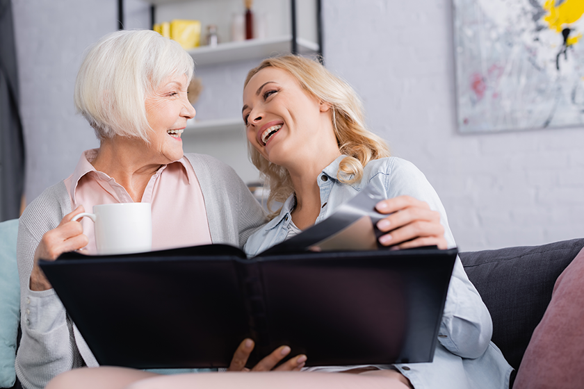 Cheerful women with cup holding photo album
