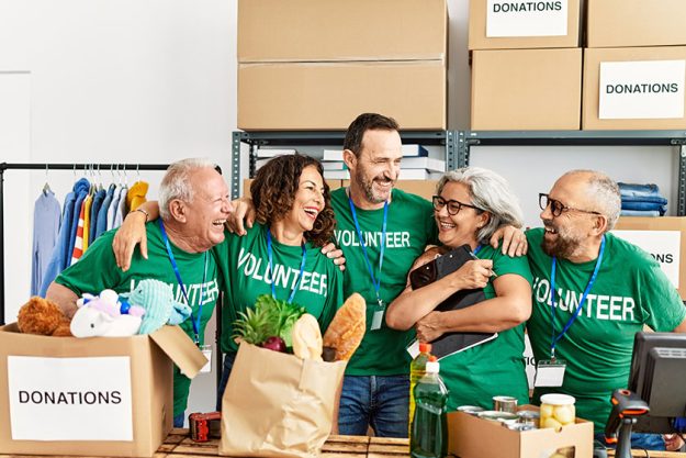 Group of middle age volunteers smiling happy and hugging standing Group of middle age volunteers smiling happy and hugging standing
