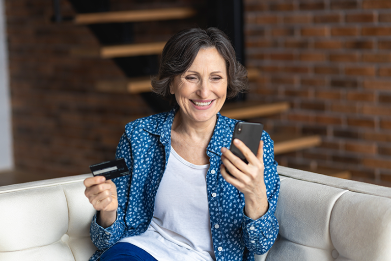 Happy elderly woman paying with credit card