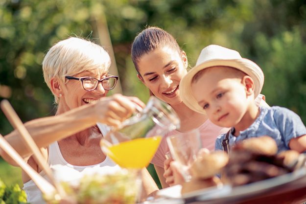 Happy family having barbecue lunch in the garden on sunny day