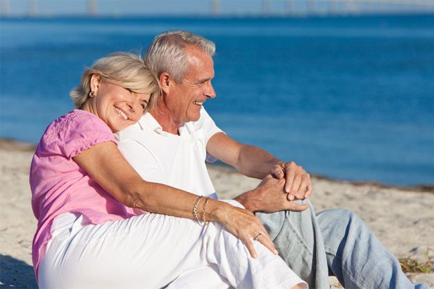 Happy Romantic Senior Couple Sitting Together on Beach Happy Romantic Senior Couple Sitting Together on Beach