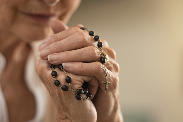 Old wrinkled hands holding a rosary Old wrinkled hands holding a rosary