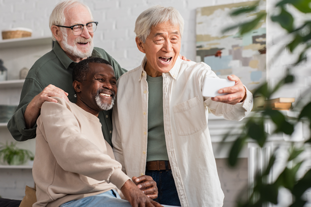 Senior asian man taking selfie near multiethnic friends at home