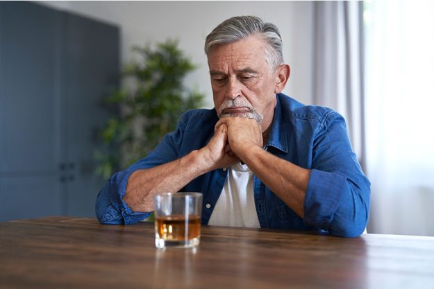 Senior caucasian man sitting and looking at the glass