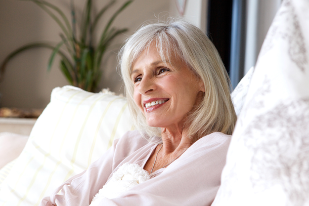 Woman sitting on couch and smiling Woman sitting on couch and smiling