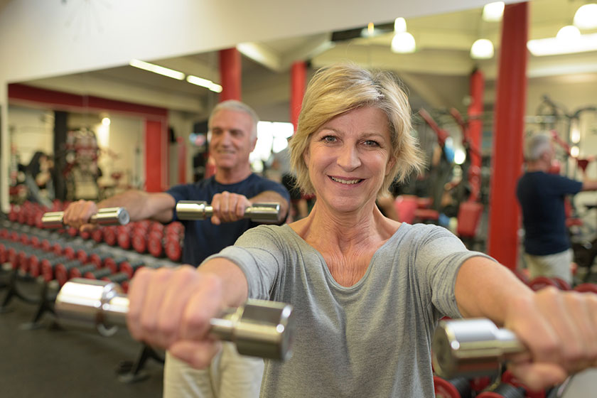 Sporty senior woman lifting gym weights