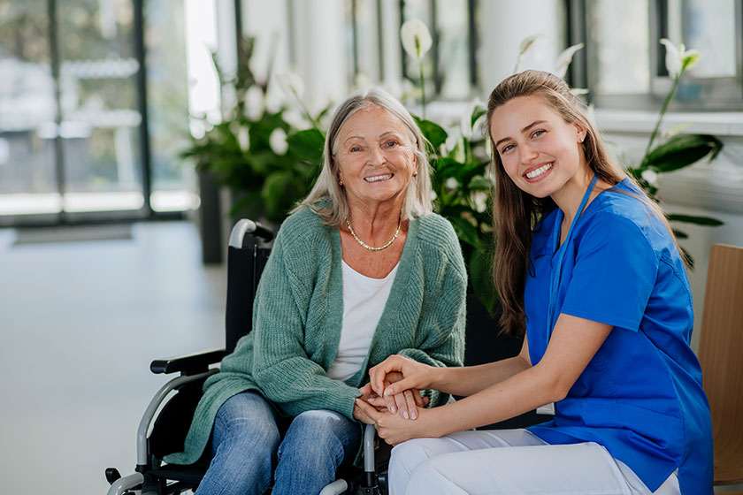 Young woman doctor taking care of senior woman at wheelchair