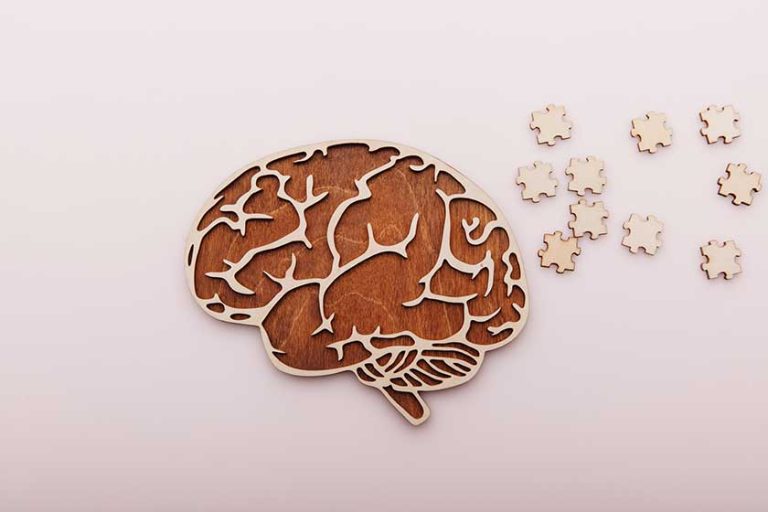 Alzheimers disease and mental health concept. Brain and wooden puzzle on a desk Alzheimers disease and mental health concept. Brain and wooden puzzle on a desk