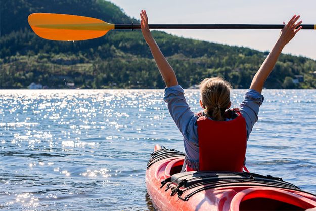 The girl holds a paddle over her head and floats