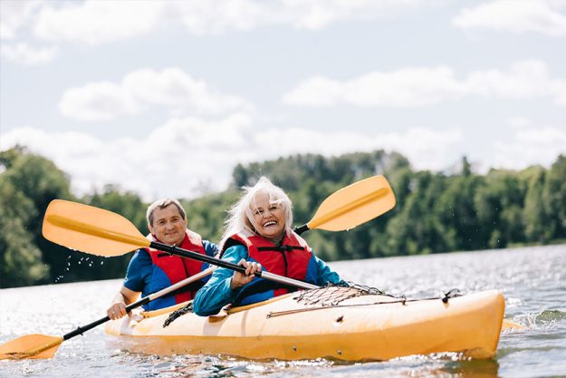 Happy senior active couple kayaking on lake