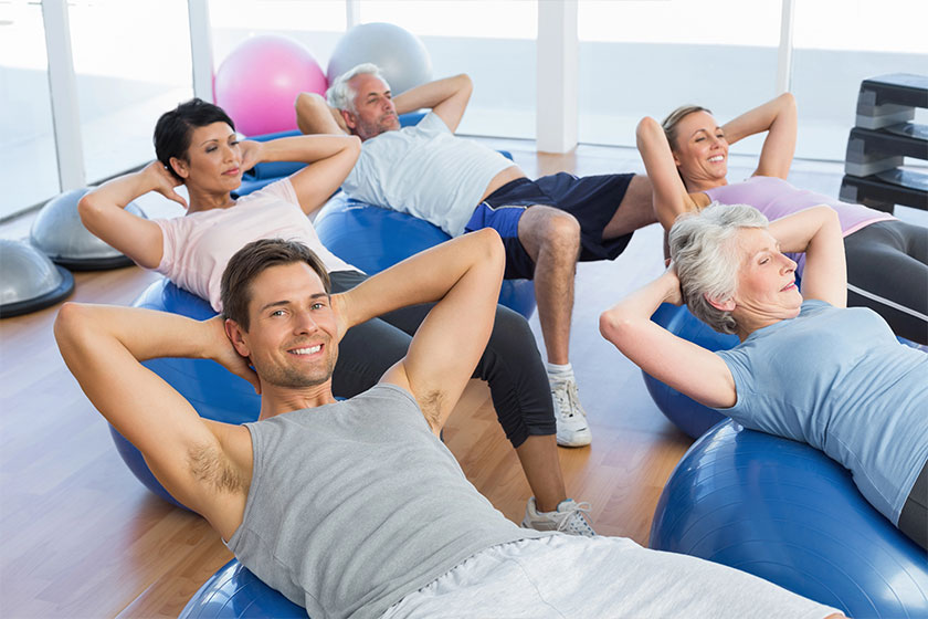 Smiling people stretching on exercise balls in gym Smiling people stretching on exercise balls in gym