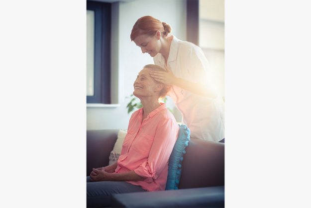 Female nurse giving head massage to woman