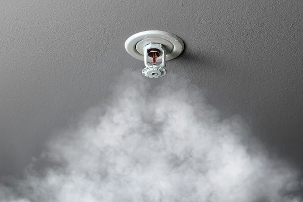 Fire alarm sprinkler system in action with smoke Fire alarm sprinkler system in action with smoke