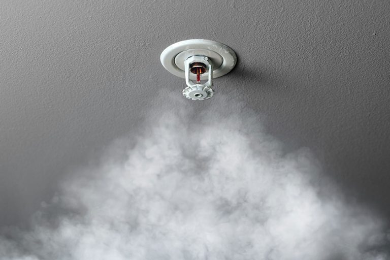 Fire alarm sprinkler system in action with smoke