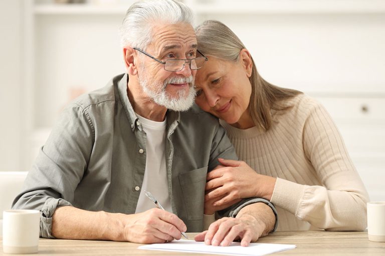 Senior couple signing Last Will and Testament indoors