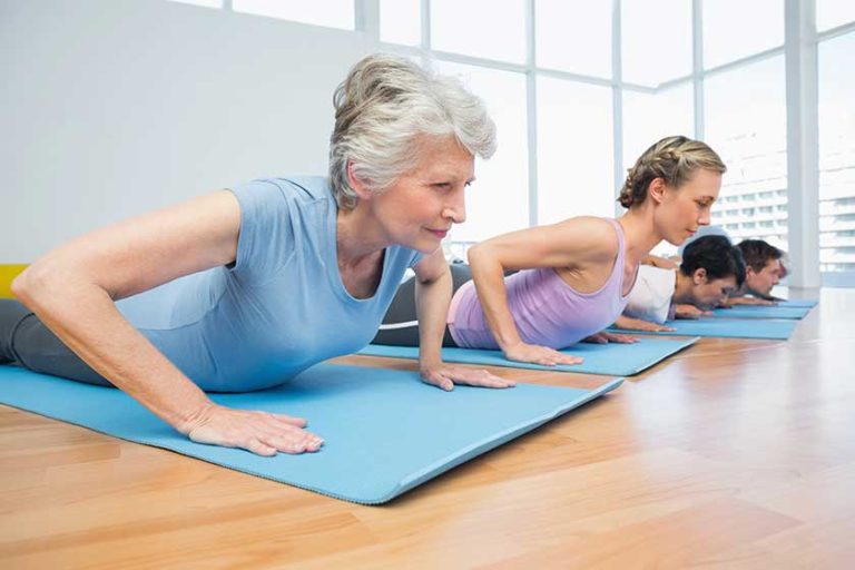 Group doing cobra pose in row at yoga class