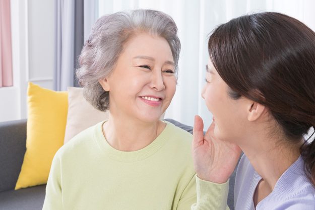 Happy smiling Asian old mother and middle aged daughter on sofa Happy smiling Asian old mother and middle aged daughter on sofa
