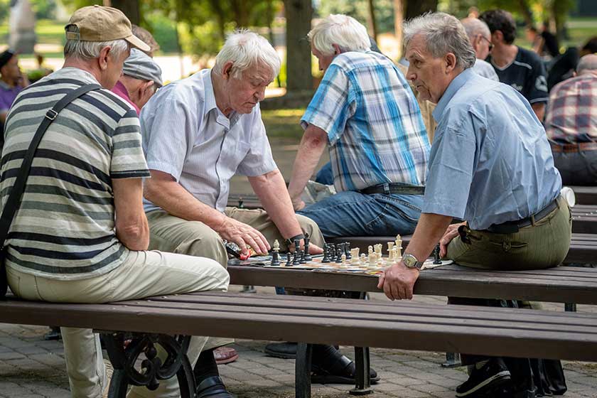 RIGA, LATVIA - JULY 18, 2018: Men seated on park benches and playing chess.