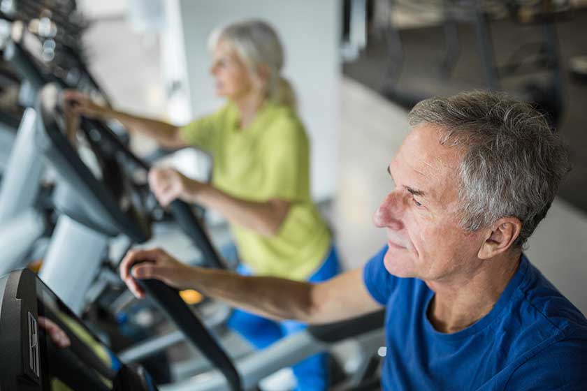 Senior man working out on stair stepper at gym Senior man working out on stair stepper at gym
