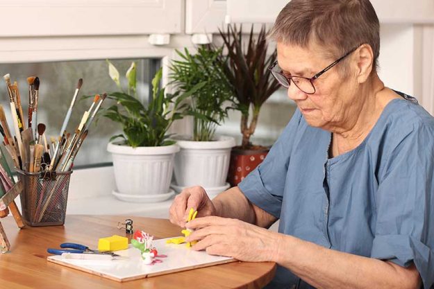 Active old age. An elderly woman sculpts small toys from polymer clay. Art therapy. the age of 80 years. A happy elderly person is engaged in creativity
