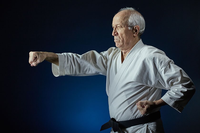 On a blue background, an old man athlete beats a punch arm