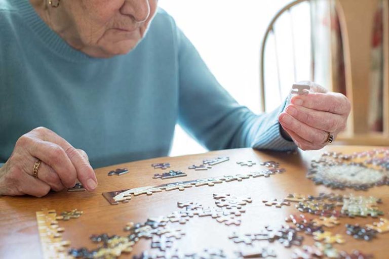 Close Up Of Senior Woman Relaxing With Jigsaw Puzzle At Home