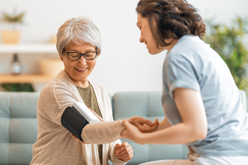 Elderly patient and caregiver measuring blood pressure.