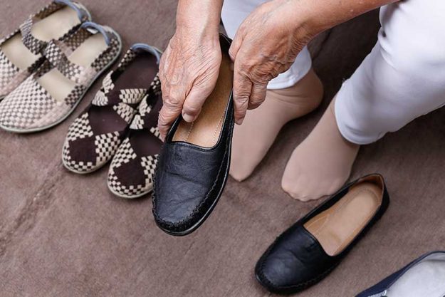 Elderly woman putting on shoes