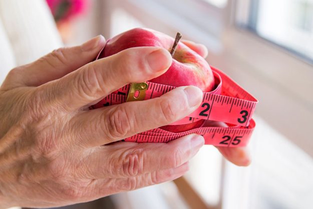 Hands with apples and tape measure, concept of diet and weight control.
