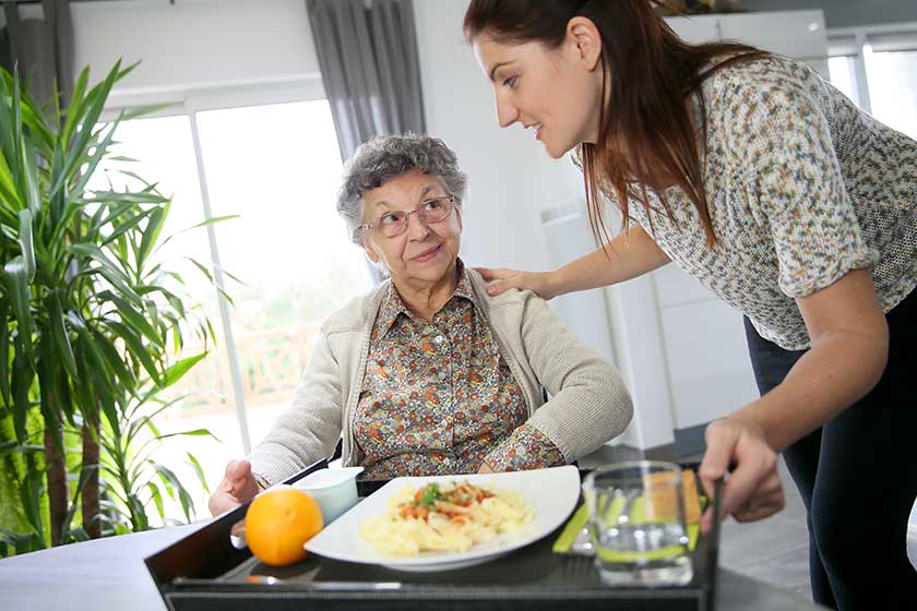 Home carer preparing lunch for woman Home carer preparing lunch for woman