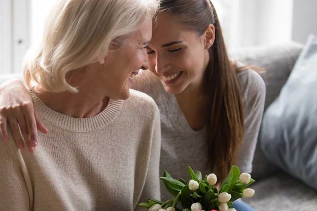 Loving adult daughter greeting mom with flowers Loving adult daughter greeting mom with flowers